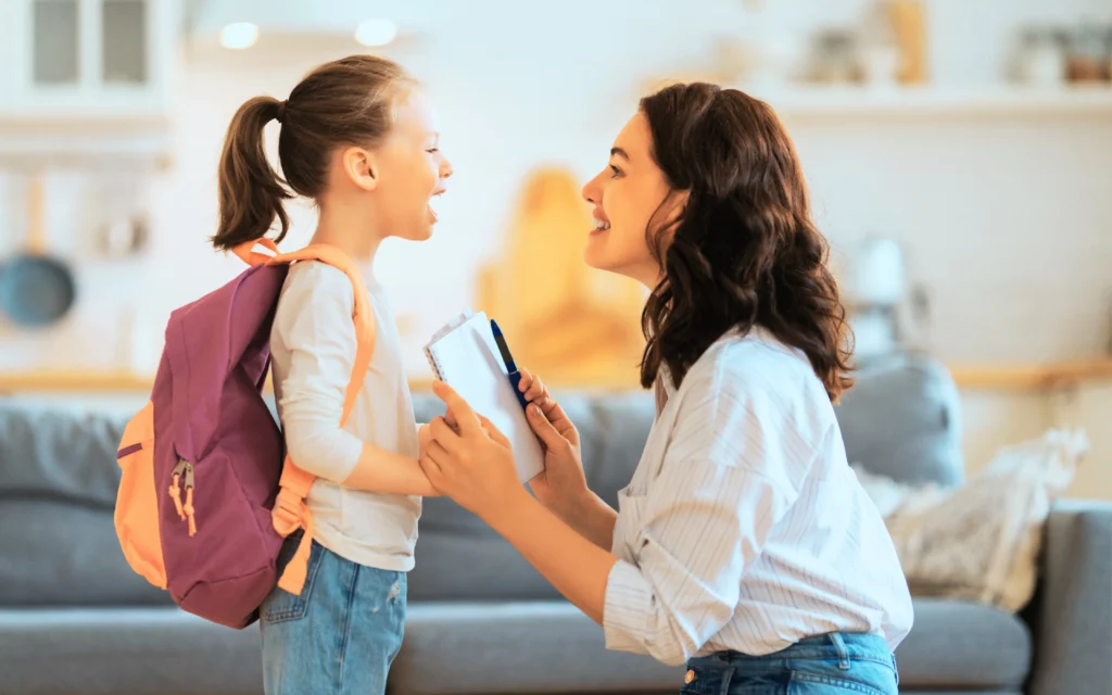 A young woman speaks with her child wearing a backpack before her first day back to school