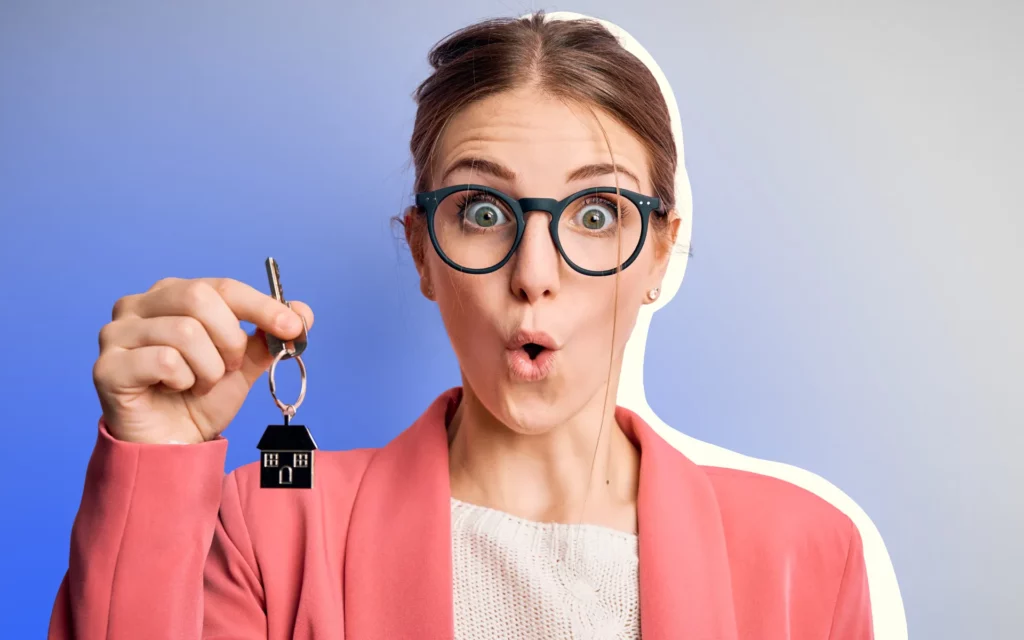 A woman with glasses holding a key to a buyer's new home