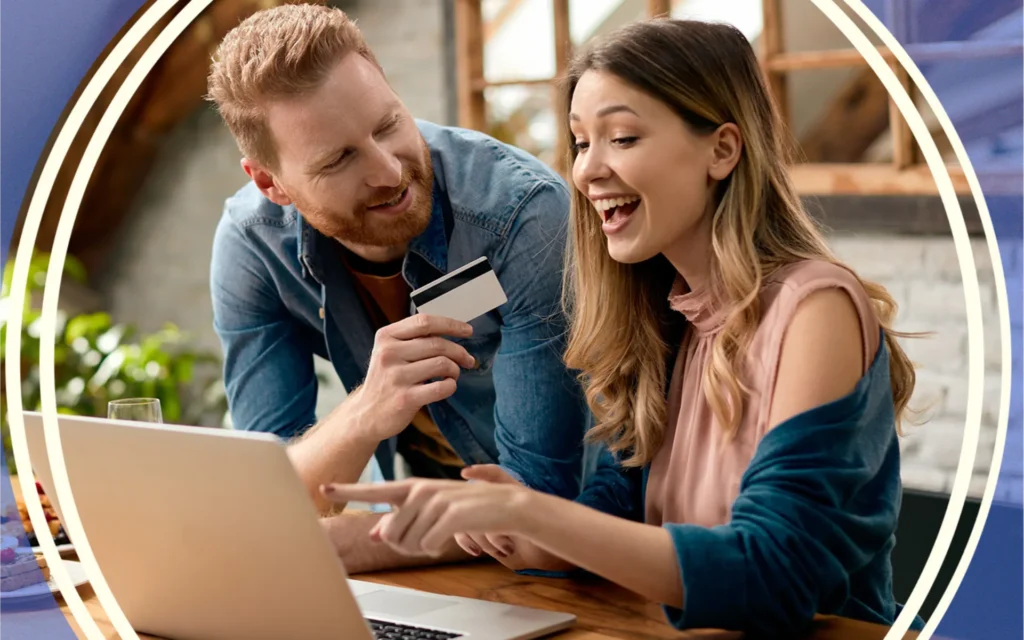 Two people excitedly look at a laptop, with one person holding a credit card